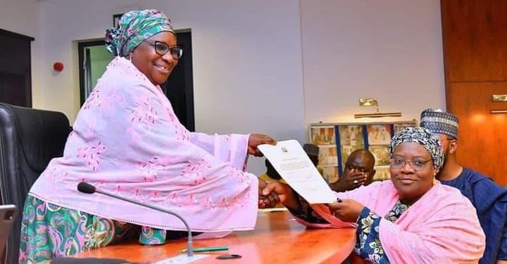 Deputy Governor of Kaduna state, Dr Hadiza Balarabe, presenting a copy of Oath of Office to Hajiya Ummah K Ahmad, after being sworn in as Commissioner of Local Government Affairs, along with five other political appointees, at the Council Chambers of Sir Kashim Ibrahim House