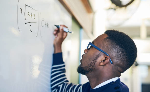 Cropped shot of a young man writing on a whiteboard in a classroom