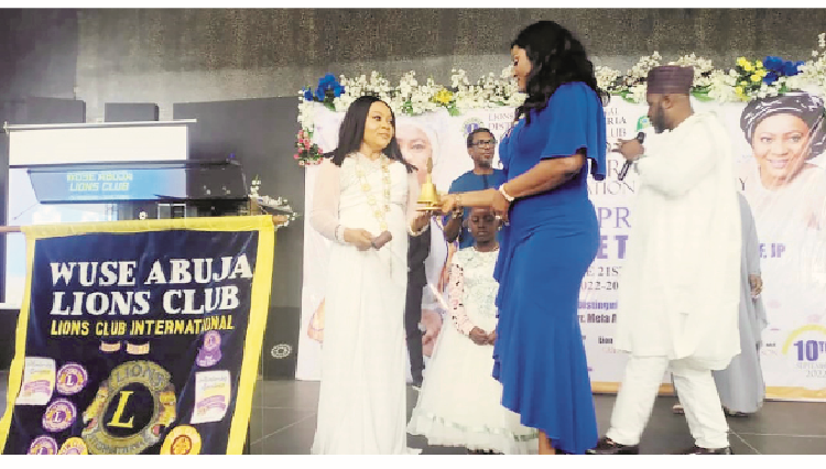 Wuse Abuja Lions Club Tamer, Lion Chika Frances Anuoro handing over the gown and gavel to the incoming president, Princess Doo Kene Tsumba NLCF,  JP to strike herself into office for the first time