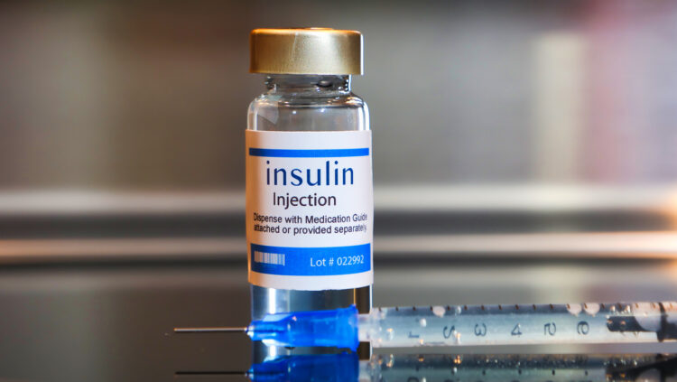 Bottle of insulin injection with a syringe on black table and stainless steel background. Pic credit: Istock