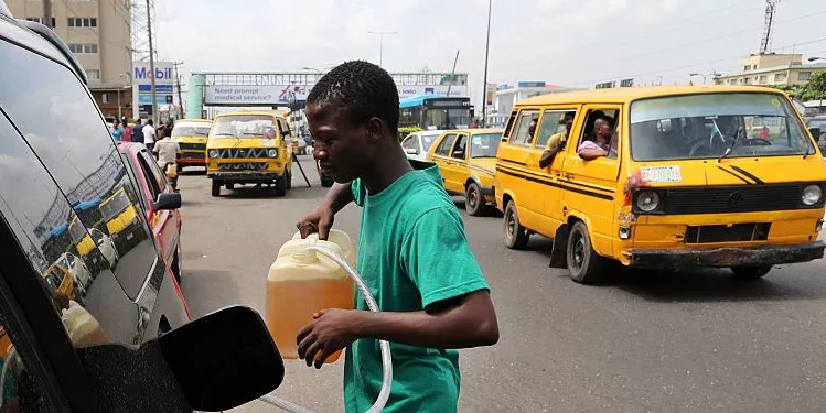 A man fills an automobile with fuel sold on the black market as others queue to buy fuel on a major road in Lagos, Nigeria, on Thursday, April 7, 2016. International energy companies in Nigeria have agreed to provide about $200 million to help fund fuel imports amid a foreign-currency shortage, which has caused widespread supply shortages Petroleum Minister of State Emmanuel Kachikwu said. Photographer: George Osodi/Bloomberg