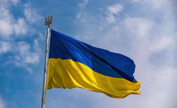 Ukrainian national official flag on flagpole waving in the wind on picturesque blue sky background