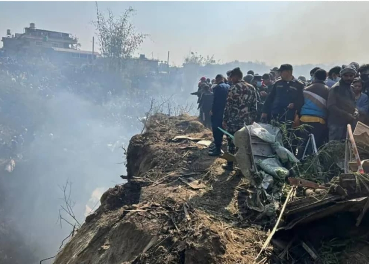 Rescuers and onlookers gather at the site of a plane crash [Krishna Mani Baral/AFP]