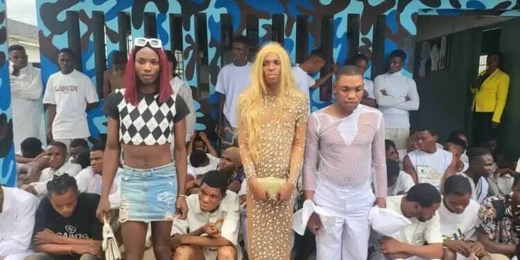 The suspected gay couple in white and gown standing and some of the suspects arrested during the police parade in Ekpan, Uvwie, Delta state. PHOTO: Felix lgbekoyi