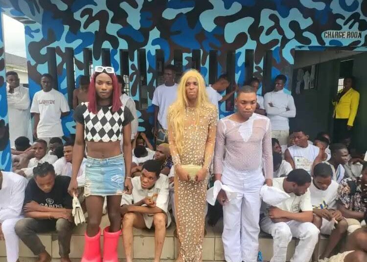 The suspected gay couple in white and gown standing and some of the suspects arrested during the police parade in Ekpan, Uvwie, Delta state. PHOTO: Felix lgbekoyi