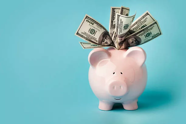 Making Money With Referral Programmes 1 "A smiling pink piggybank stuffed with $100 dollar bills, on blue background with copy space. You may also like:"