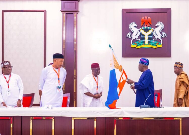 President Bola Tinubu, presenting the All Progressives Congress (APC) flag to the party's gubernatorial candidate in Edo State, Senator Monday Okpebholo, and his running mate, Hon. Dennis Idahosa