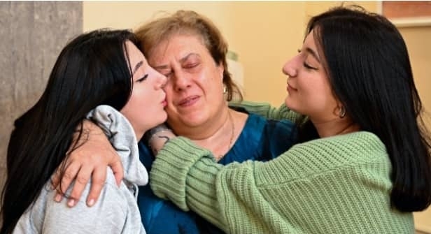 Georgian twin sisters Anna Panchulidze (L), Elene Deisadze (R), and Elene’s adoptive mother, Lia Korkotadze. (Photo by Vano SHLAMOV/AFP)