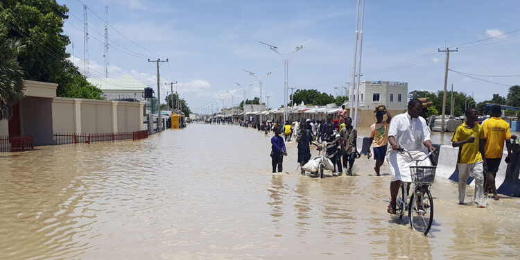People walk through floodwaters following a dam collapse in Maiduguri, Nigeria, Tuesday Sept 10, 2024. (AP Photos/ Joshua Olatunji)