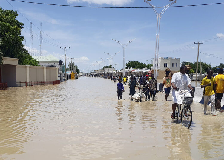 People walk through floodwaters following a dam collapse in Maiduguri, Nigeria, Tuesday Sept 10, 2024. (AP Photos/ Joshua Olatunji)