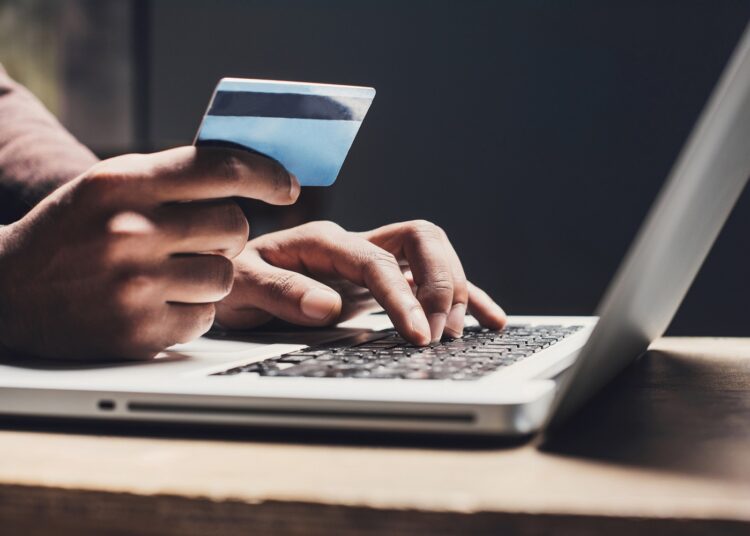 Men entering credit card information using laptop computer keyboard. Online shopping concept