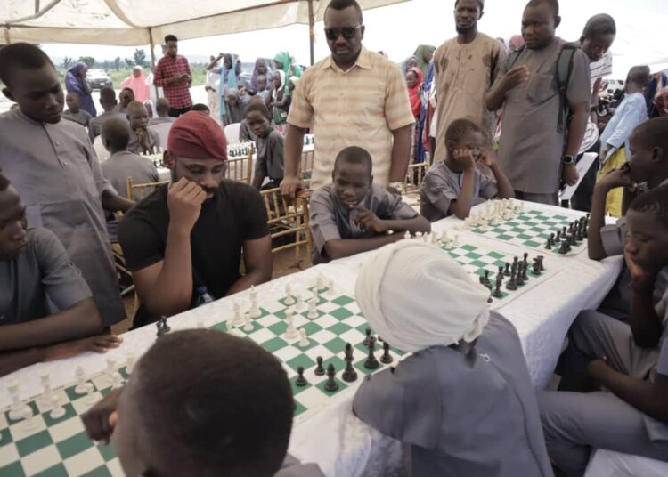 Onakoya and the children playing chess at Malhohi IDP camp in Adamawa State.