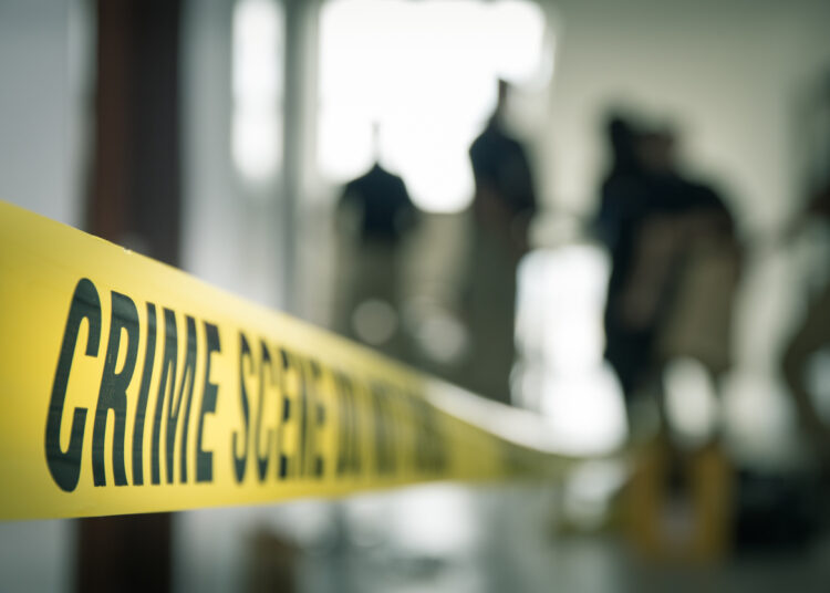 crime scene tape with blurred forensic law enforcement background in cinematic tone and copy space