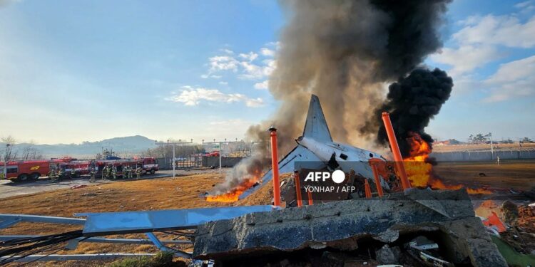 fire and smoke rise from the tail section of a Jeju Air Boeing 737-800 series aircraft after the plane crashed and burst into flames at Muan International Airport in South Jeolla Province, some 288 kilometres southwest of Seoul on December 29, 2024. - A Jeju Air plane carrying 181 people from Bangkok to South Korea crashed on arrival on December 29, authorities told AFP, with 29 confirmed dead and dramatic video showing the aircraft bursting into flames. (Photo by YONHAP / AFP) / - South Korea OUT / NO USE AFTER JANUARY 8, 2025 02:48:46 GMT -  - SOUTH KOREA OUT / NO ARCHIVES -  RESTRICTED TO SUBSCRIPTION USE