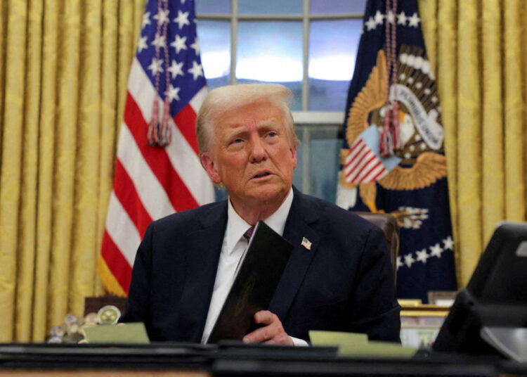 FILE PHOTO: U.S. President Donald Trump signs documents as he issues executive orders and pardons for Jan. 6 defendants in the Oval Office at the White House on Inauguration Day in Washington, U.S., January 20, 2025. REUTERS/Carlos Barria/File Photo