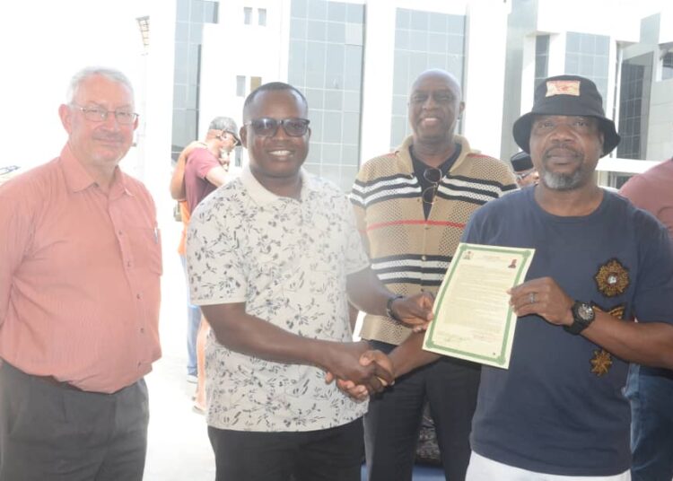 Owner of the River Park Estate, Abuja, Mr. Paul Odili (right) presenting a Certificate of Occupancy to one of the beneficiaries on Saturday. With him are Dr. Adrian Ogun and Mr. John Townley-Johnson, CEO of Houses for African Holdings, at the handing-over ceremony at the estate on Saturday.