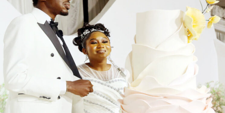 The newly married, Iyanuoluwa and Adedayo, and their wedding cake during the reception