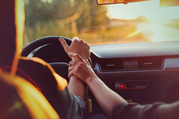 Are You A Blind Driver? 1 The couple drives the car on the way to the sunset. He drives the car, she holds his hand. Shooting close-up. Support for loved ones. Go to the sunset. Travel of lovers.