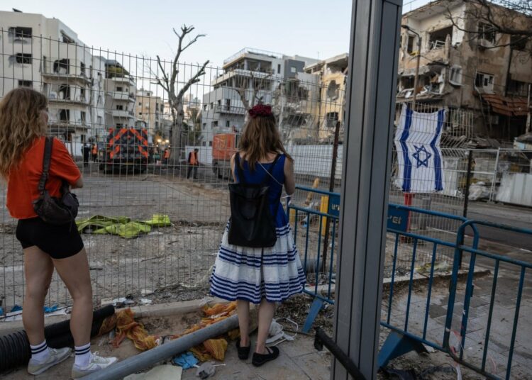 People visit the site of an Iranian missile attack in central Tel Aviv which left several destroyed buildings, on June 16, 2025. Israel and Iran traded heavy fire for a fourth straight day on June 16, with mounting casualties and expanding targets marking a sharp escalation in hostilities between the longtime foes. (Photo by Menahem Kahana / AFP)