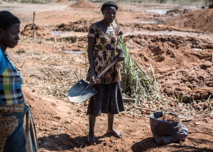 A woman fills a bag in a mine between Lubumbashi and Kolwezi on May 31, 2015. AFP PHOTO/FEDERICO SCOPPA        (Photo credit should read FEDERICO SCOPPA/AFP/Getty Images)
