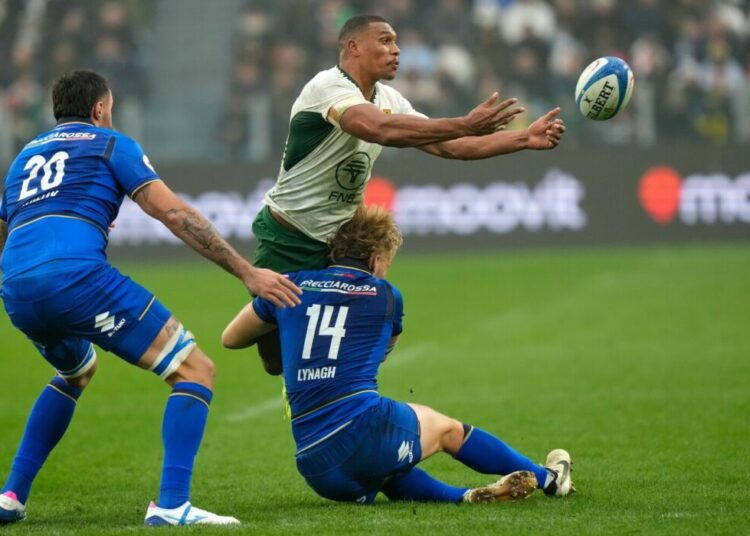 South Africa's Damian Willemse passes as Italy's Louis Lynagh makes a tackle during the rugby union Nations Series match between Italy and South Africa, in Turin, Italy, Saturday, Nov. 15, 2025. (AP Photo/Luca Bruno)
