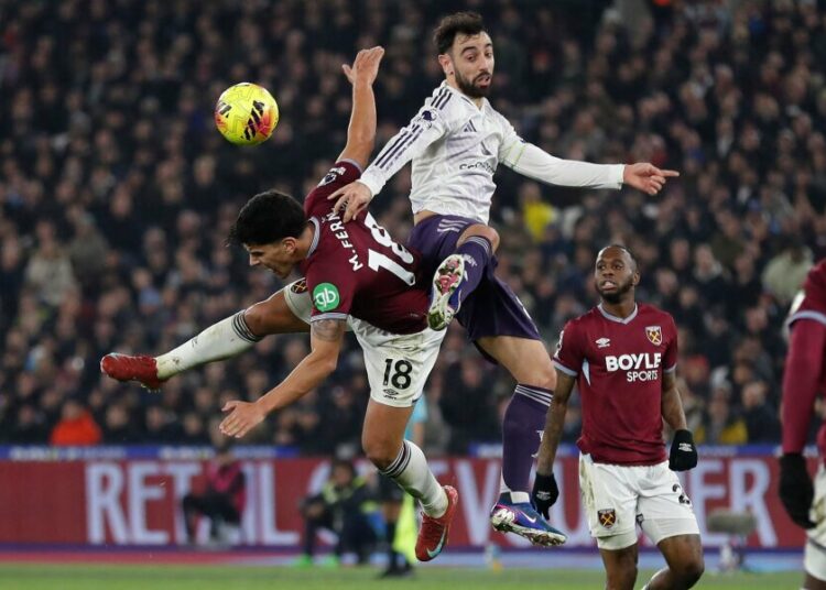 TOPSHOT - West Ham United's Portuguese midfielder #18 Mateus Fernandes (L) vies with Manchester United's Portuguese midfielder #08 Bruno Fernandes (C) during the English Premier League football match between West Ham United and Manchester United at the London Stadium in east London on February 10, 2026. (Photo by Ian Kington / AFP) / RESTRICTED TO EDITORIAL USE. No use with unauthorized audio, video, data, fixture lists, club/league logos or 'live' services. Online in-match use limited to 120 images. An additional 40 images may be used in extra time. No video emulation. Social media in-match use limited to 120 images. An additional 40 images may be used in extra time. No use in betting publications, games or single club/league/player publications. /