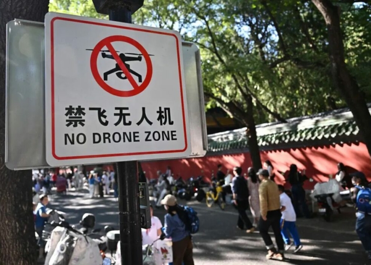 China Bans Drone Possession In Beijing Over Security Fears 1 People walk past a sign reading “No drone zone” in an alley in Beijing on September 14, 2026. Beijing will ban the possession of drones within city limits under new rules from November, further tightening regulations that already prohibited the sale of the devices. (Photo by Pedro PARDO / AFP)